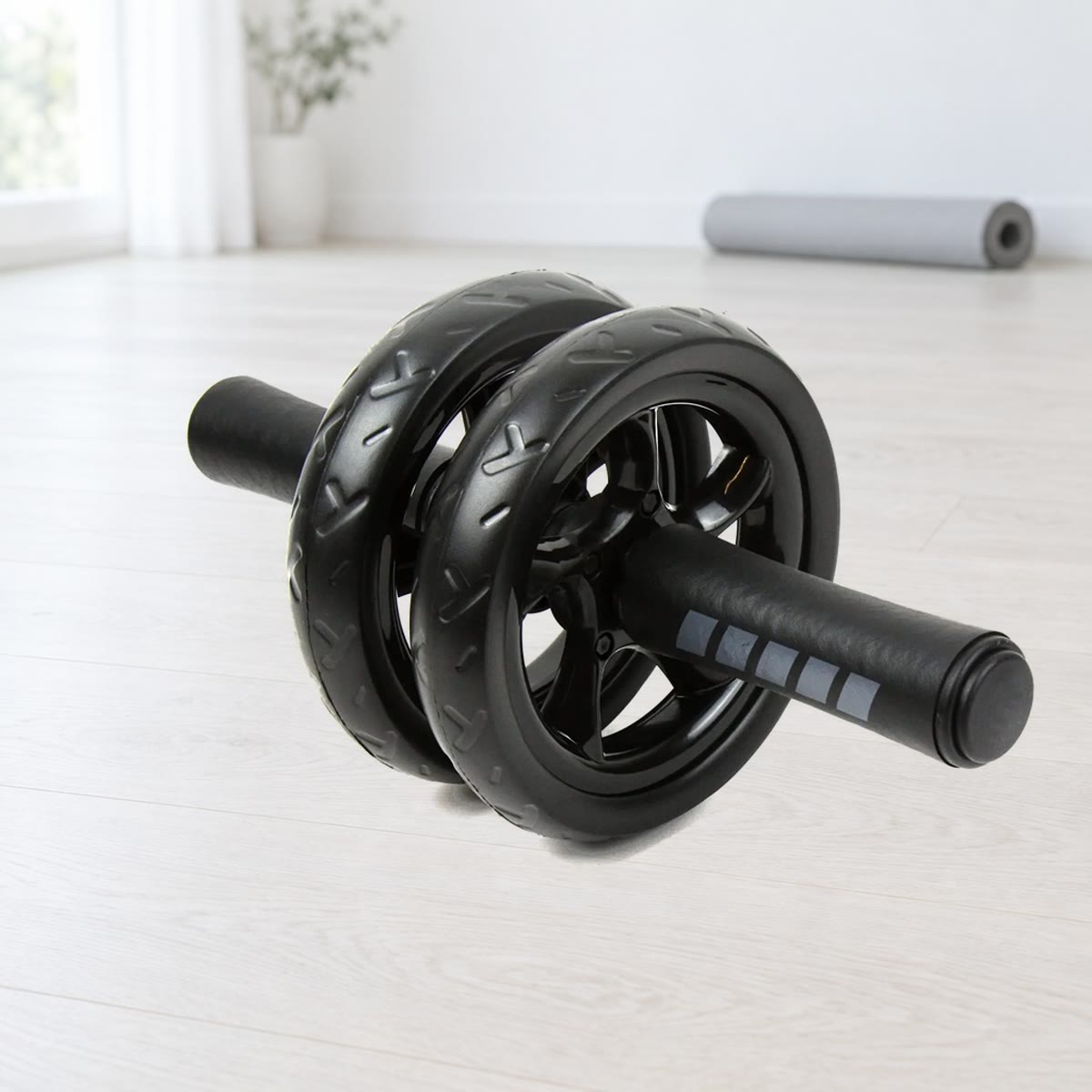 Ab wheel med to sorte, mønstrede hjul og skumhåndtag med grå striber på et lyst trægulv