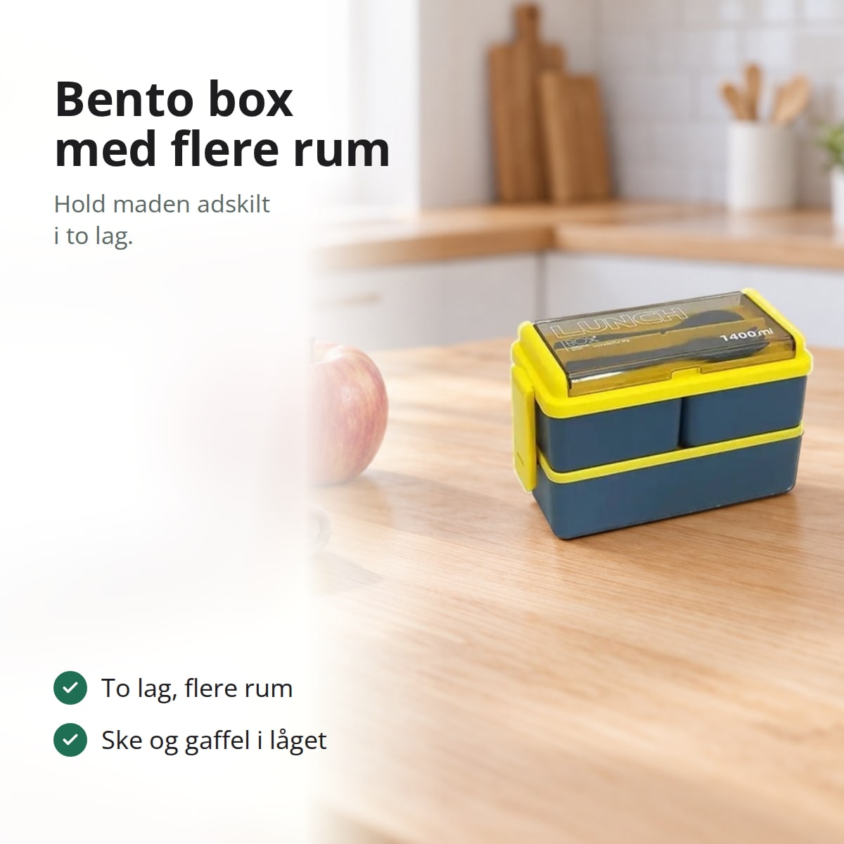 Blå og gul madkasse med to lag på et køkkenbord, med teksten: to lag med flere rum, ske og gaffel i låget