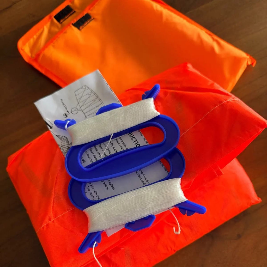 Indholdet i pakken: orange pose med velcro, sammenfoldet drage, to blå håndtag med opviklet line og brugsanvisning