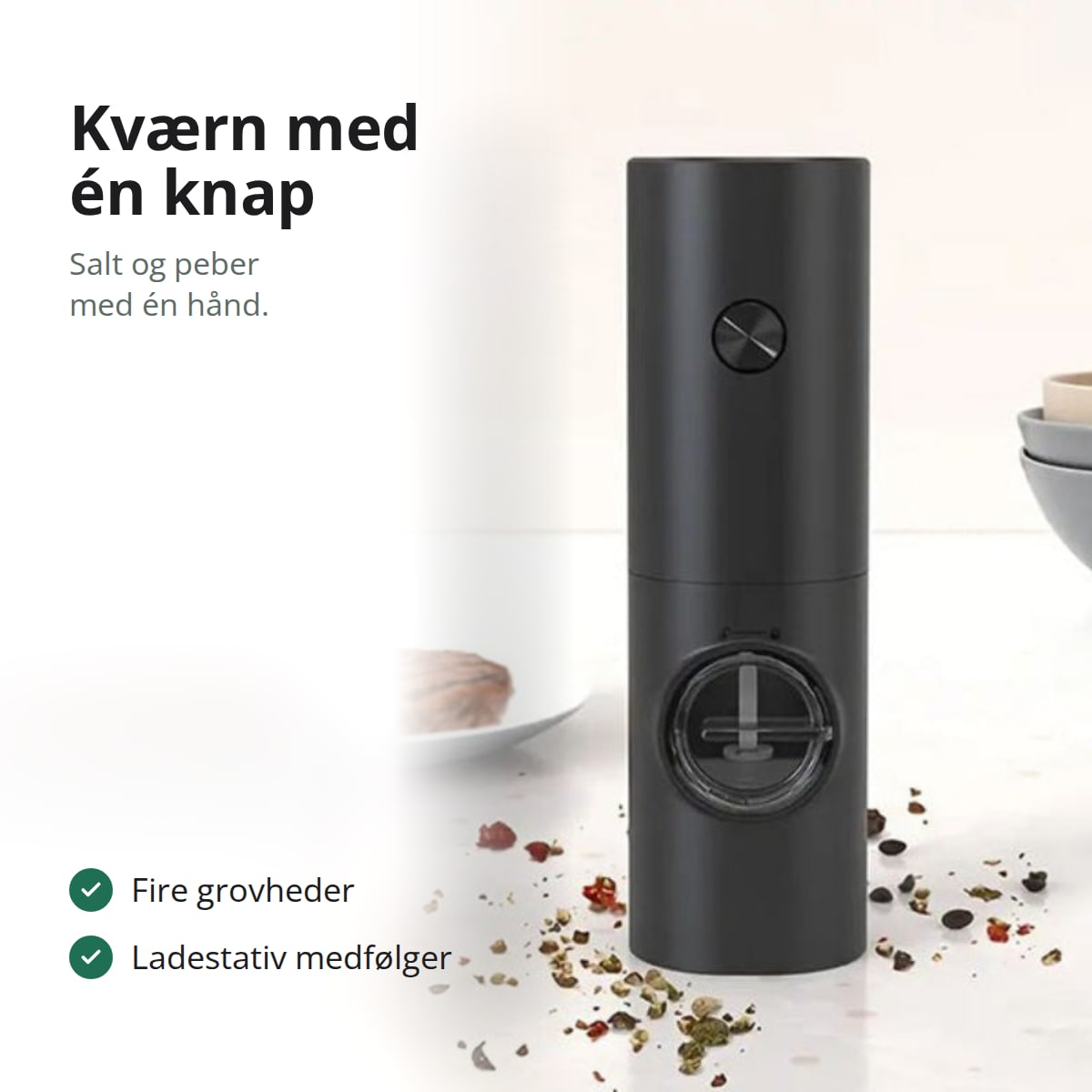 Sort elektrisk peberkværn på et lyst køkkenbord, med teksten: kværn med én knap, salt og peber med én hånd, fire grovheder, ladestativ medfølger