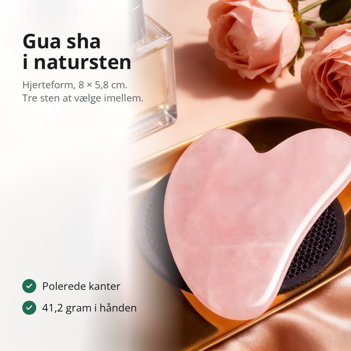 Hjerteformet gua sha i rosenkvarts på et guldfad ved siden af roser