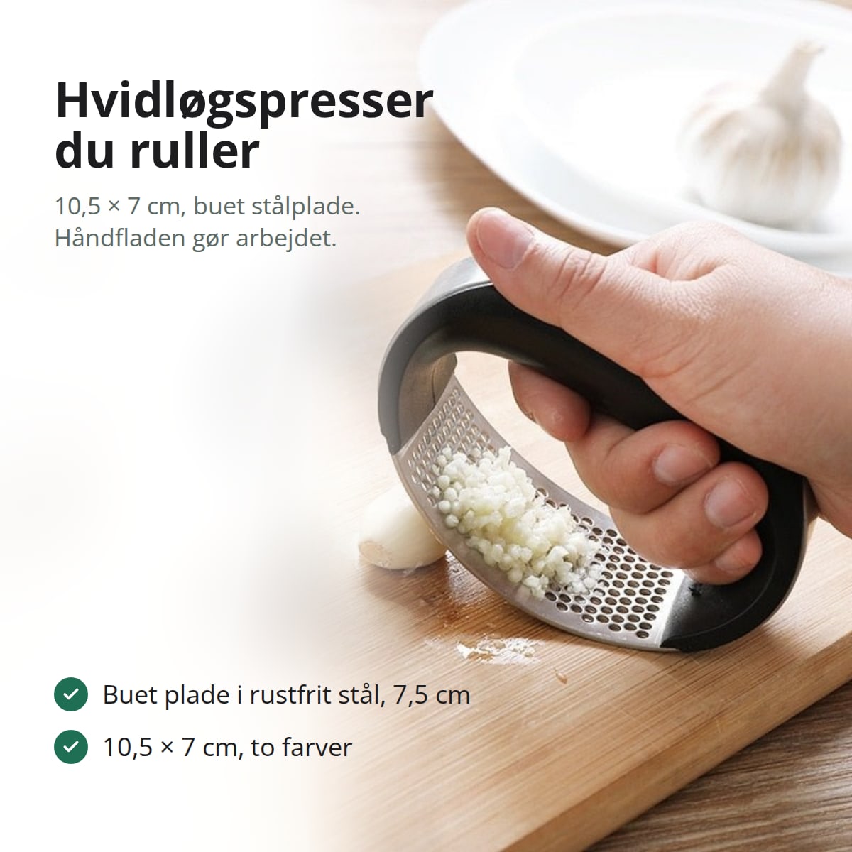Hånd ruller hvidløgspresseren hen over et hvidløgsfed på et skærebræt, med teksten: buet plade i rustfrit stål, 10,5 × 7 cm