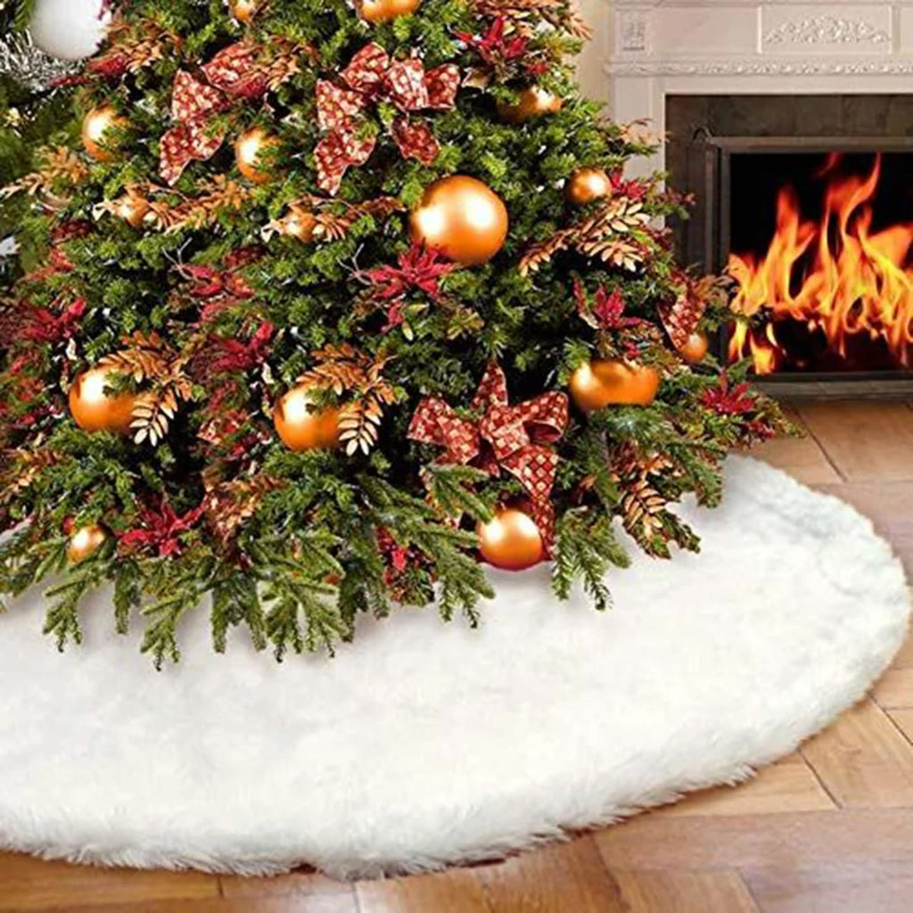 Hvidt juletræstæppe i plys om foden af et juletræ med guldkugler