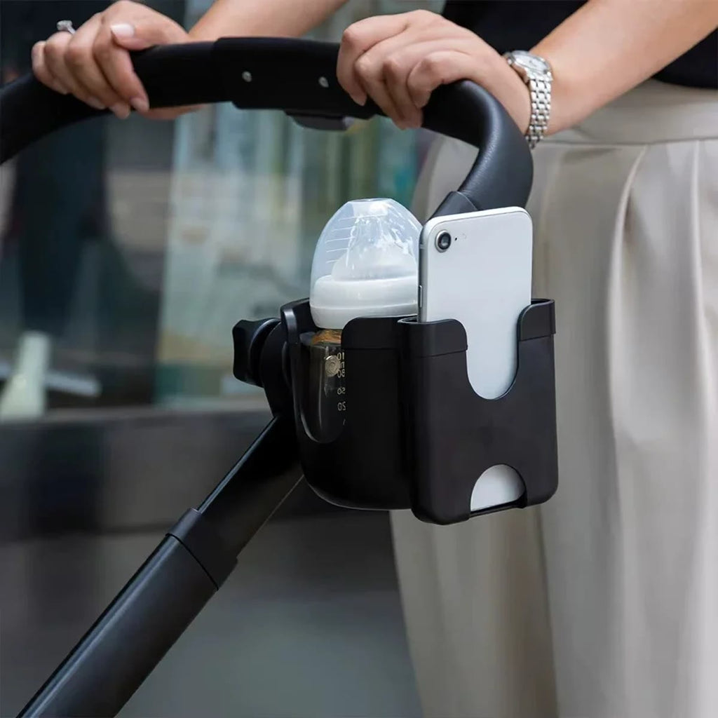 Sort kopholder på håndtaget af en barnevogn med sutteflaske og mobil