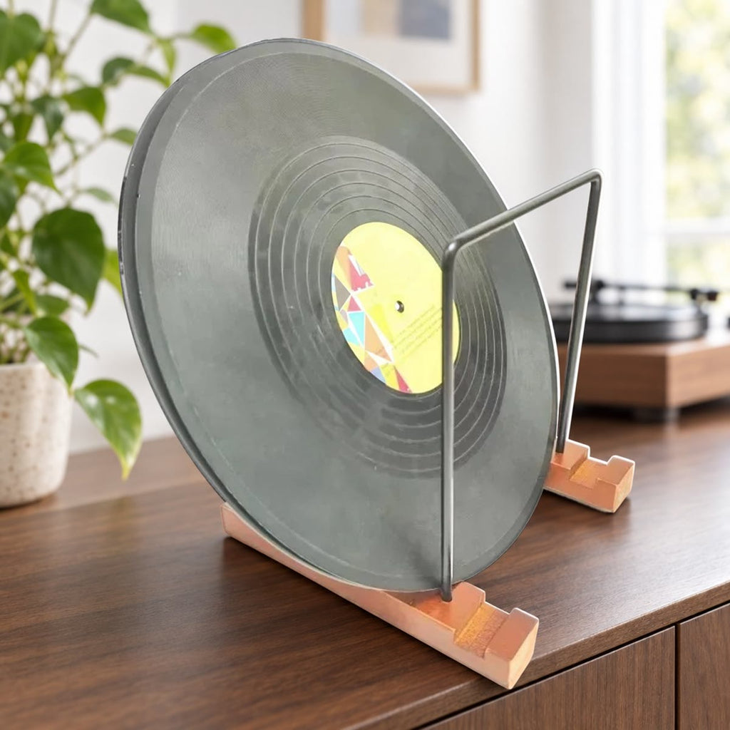 Vinylplade, der står i en pladeholder med fødder i træ og rammer i sort metal, på en skænk i valnød