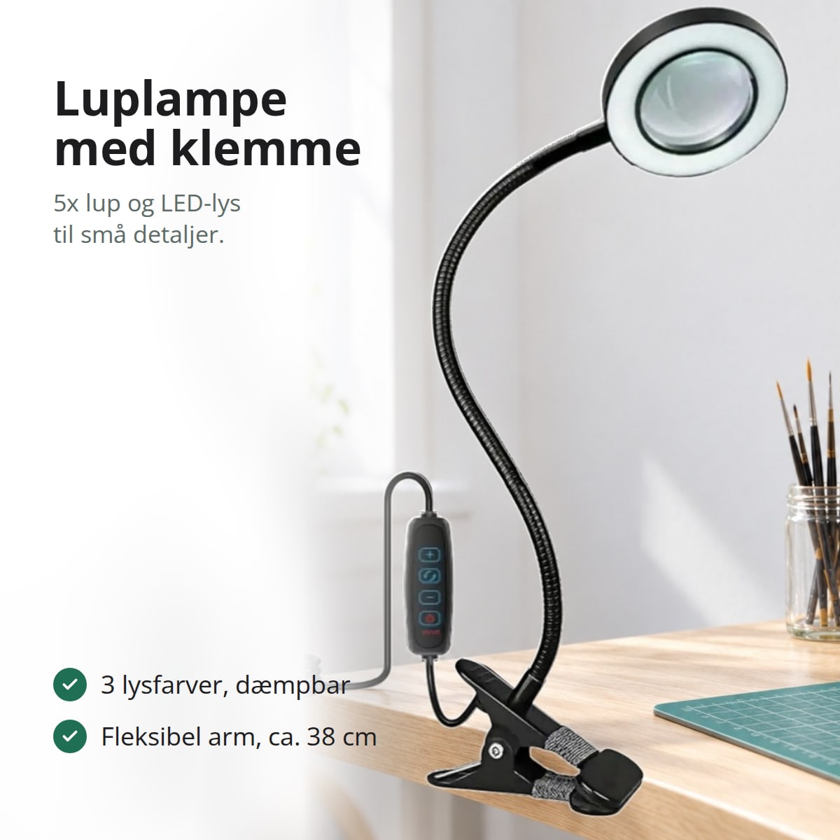 Sort luplampe med klemme, fleksibel arm og lysende LED-ring på et hobbybord med pensler og en figur, med teksten: 5x lup og LED-lys til små detaljer, tre lysfarver, fleksibel arm på ca. 38 cm