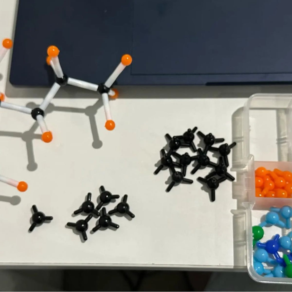Købers færdige model af et carbonskelet med hydrogenatomer på et hvidt skrivebord ved siden af æsken med delene