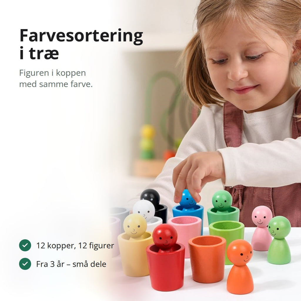 Pige, der sorterer små træfigurer i kopper med samme farve på et bord
