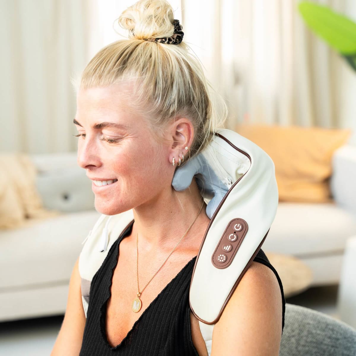 Nærbillede af massagepuden om nakken med knapperne til varme og tilstand synlige
