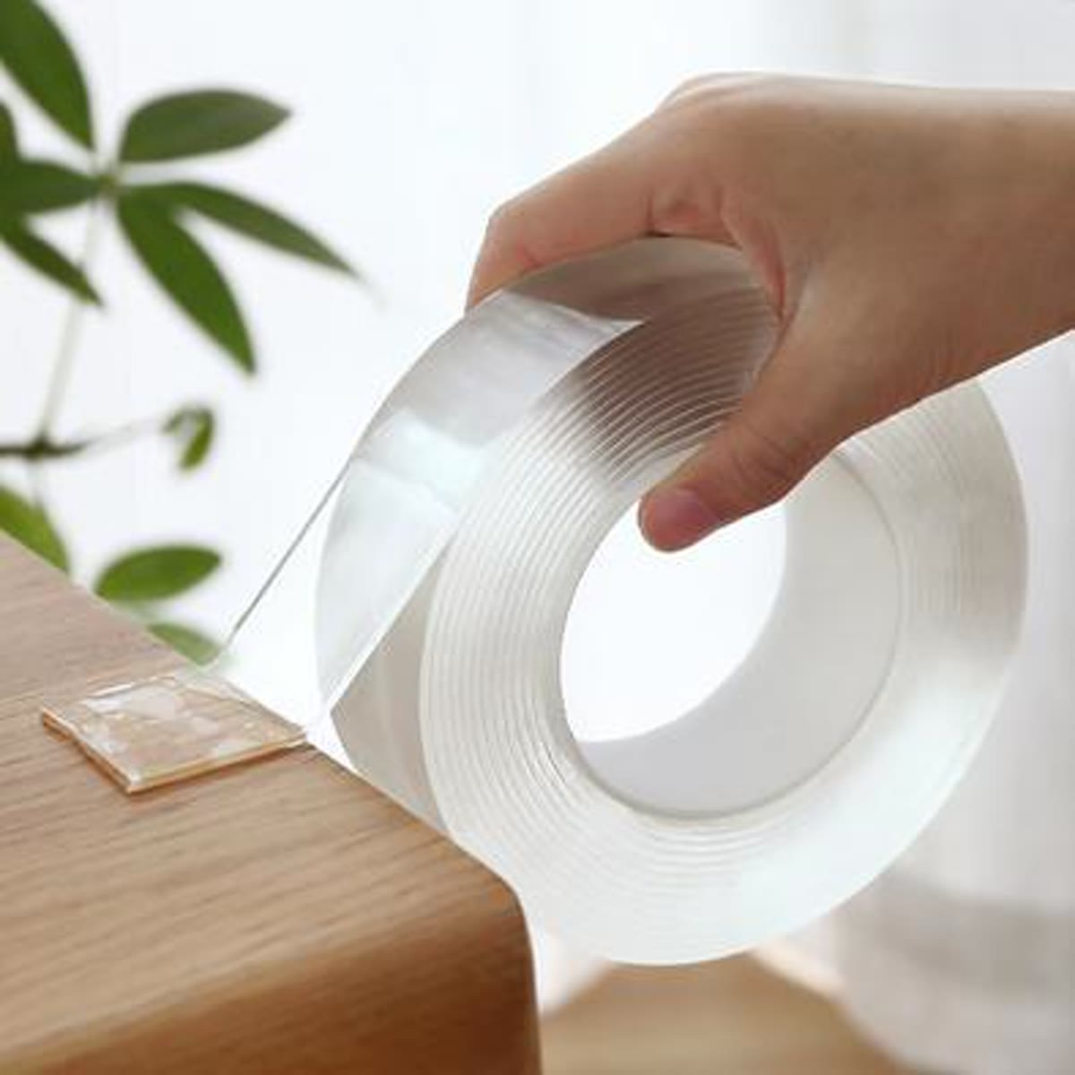Hånd, der trækker den gennemsigtige nano tape ud fra rullen på kanten af en hylde