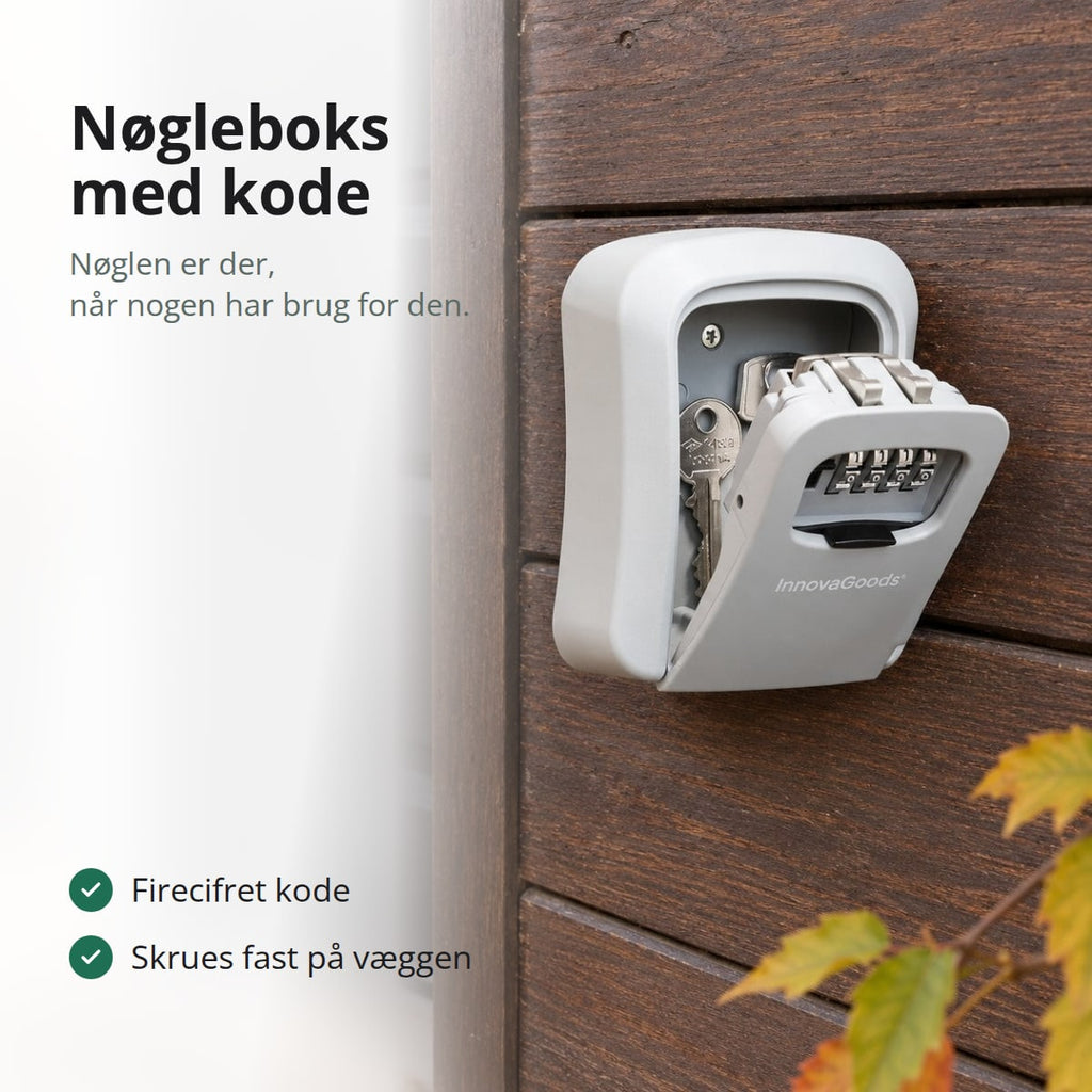 Åben grå nøgleboks med nøgler indeni på en væg af mørkt træ