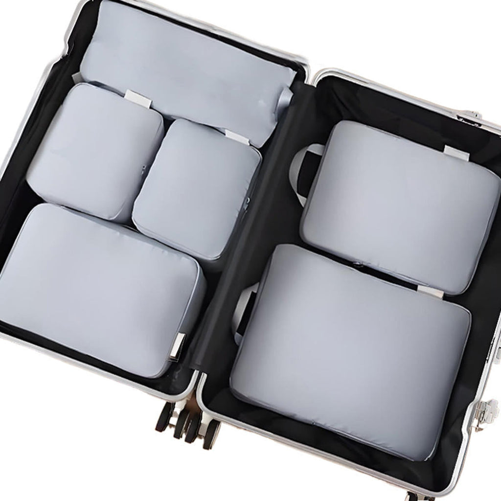 Packing cubes i grå: seks pakkeposer lagt fladt i en åben kuffert, set ovenfra