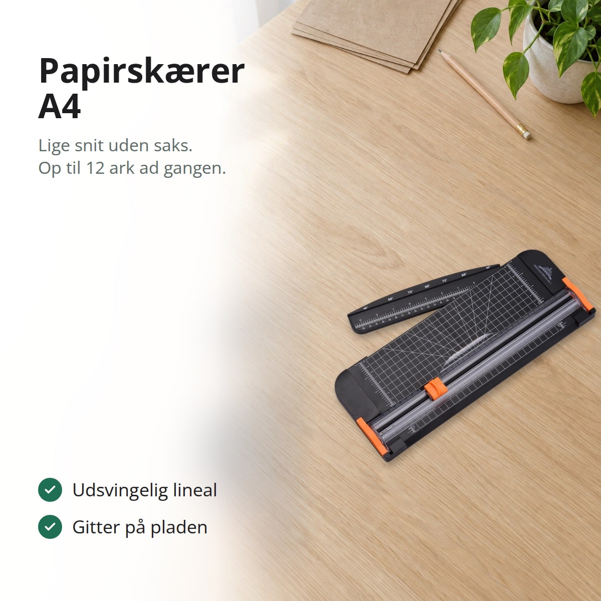 Sort papirskærer med orange skærehoved og lineal på et lyst skrivebord