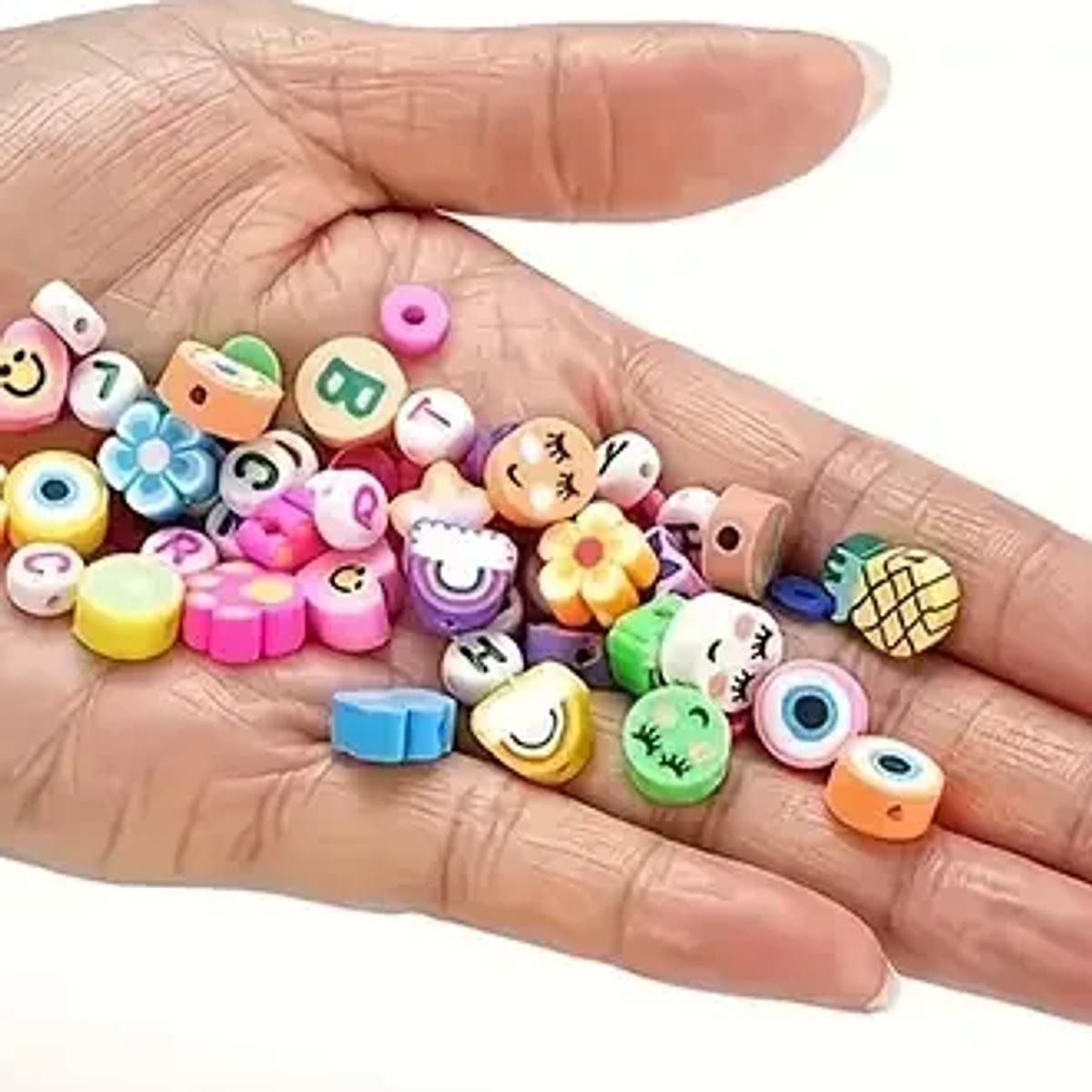 Lerperler med motiv og små lerskiver i en hånd, som viser, hvor små perlerne er; motiverne i sættet kan variere