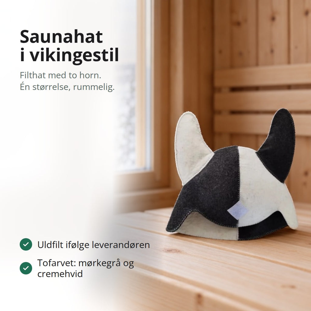 Saunahat i filt med to horn, tofarvet i mørkegrå og cremehvid, stående på en saunabænk ved et vindue ud mod en snedækket sø