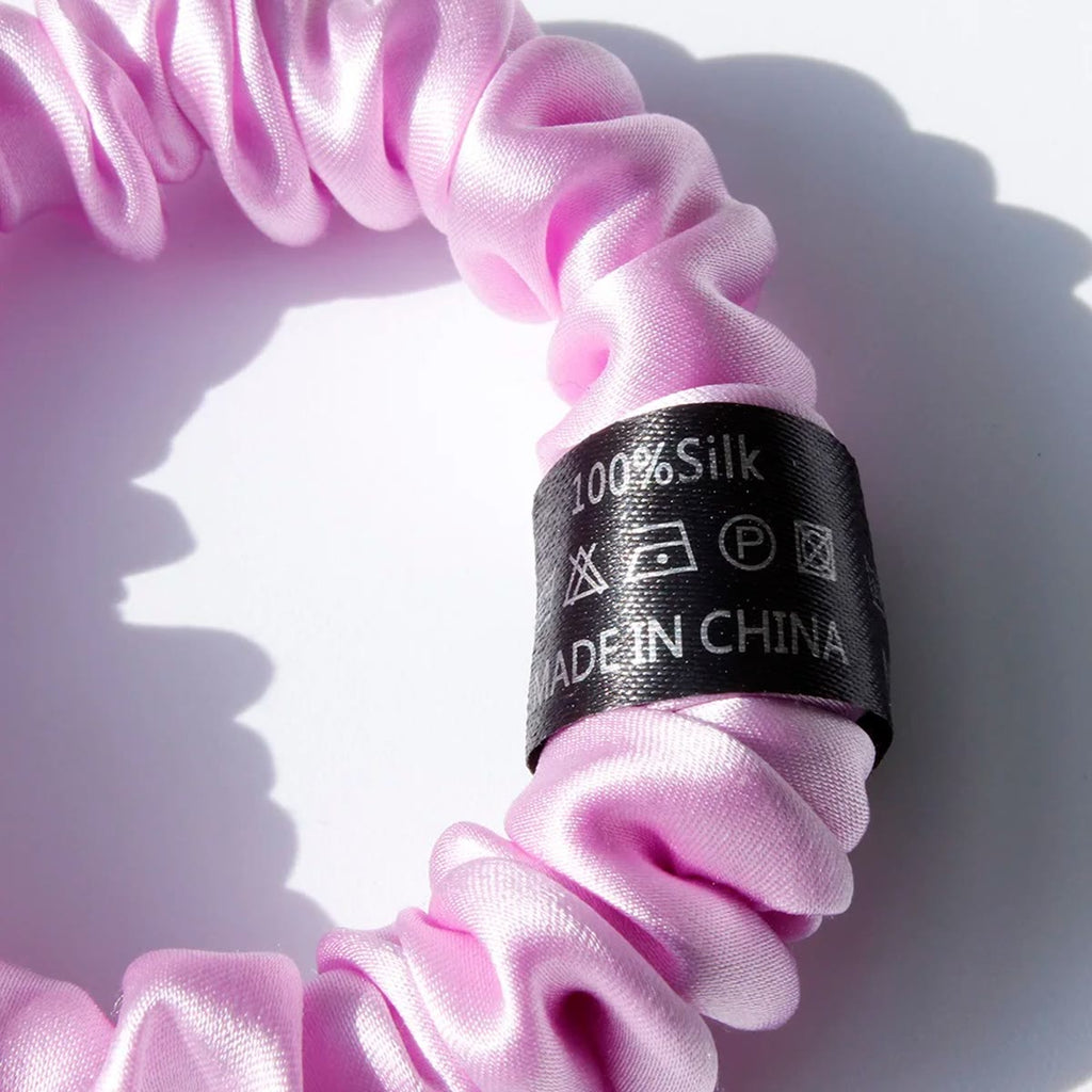 Nærbillede af etiketten 100% Silk på en rosa-lilla silke scrunchie