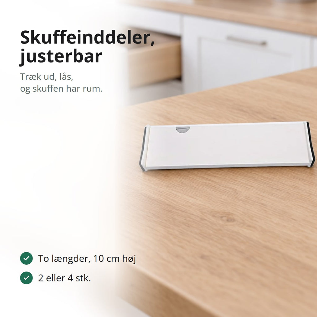 Hvid justerbar skuffeinddeler på en bordplade af lyst træ foran en åben køkkenskuffe