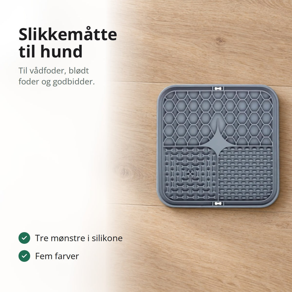 Grå slikkemåtte til hund på et egetræsgulv ved en hvid madskål, med teksten: slikkemåtte til hund, til vådfoder, blødt foder og godbidder, tre mønstre i silikone, fem farver