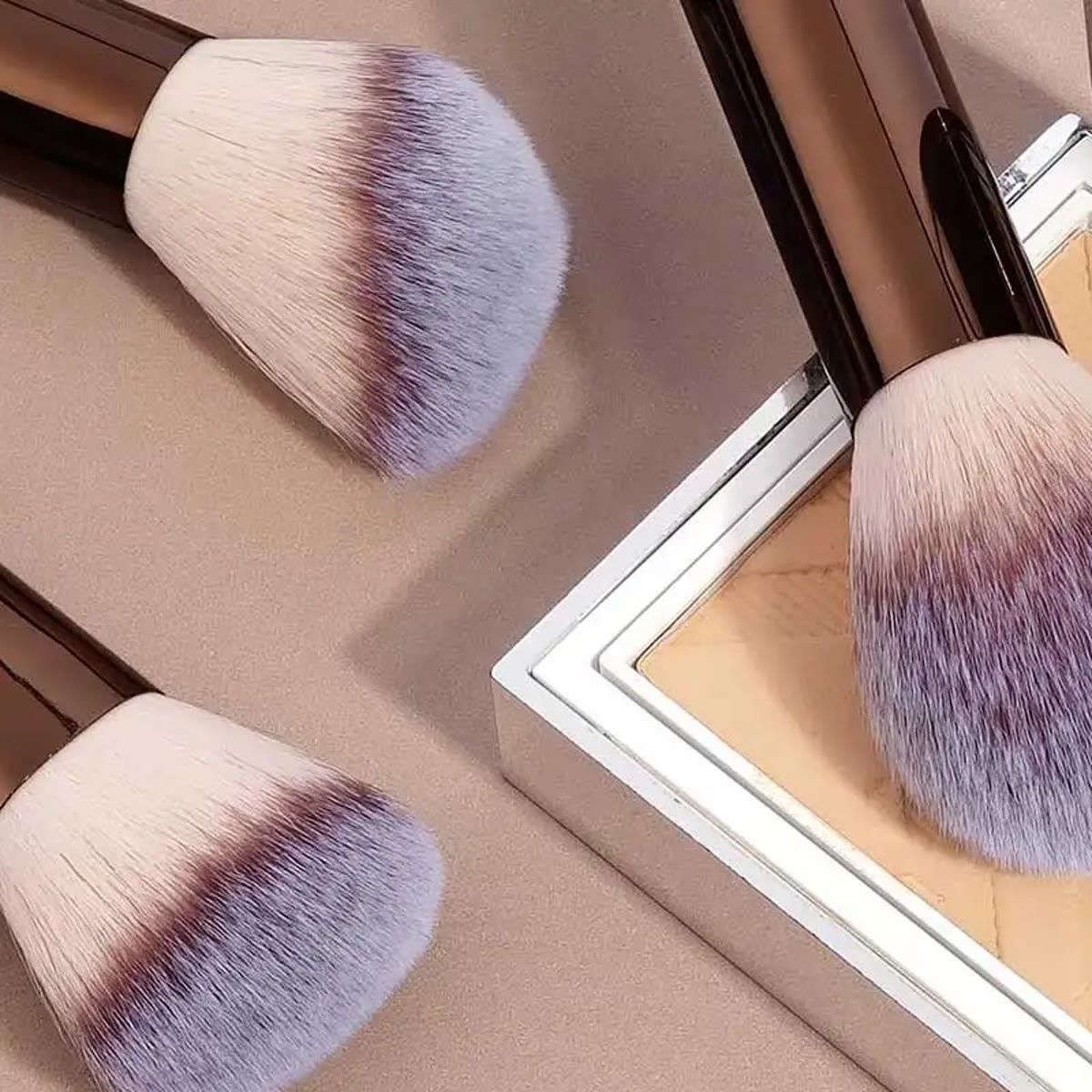 Store makeup børster ved siden af en pudderdåse