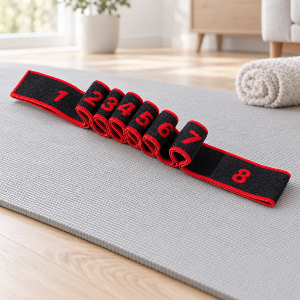 Træningselastik i sort med rød kant og otte nummererede løkker på en grå yogamåtte