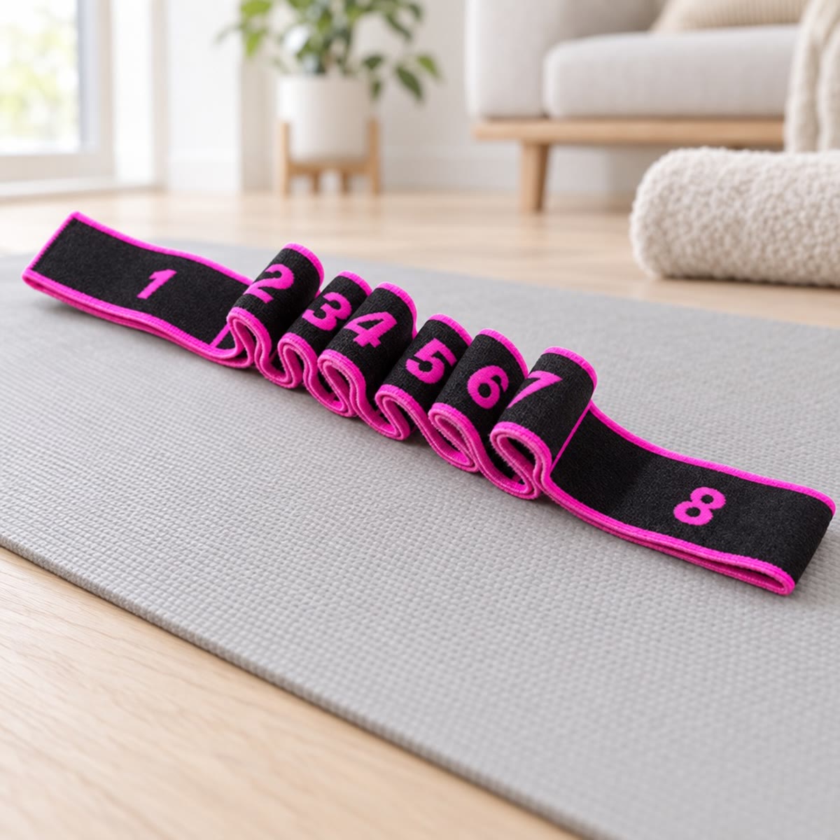 Træningselastik med magenta kant og tal på løkkerne, liggende på en yogamåtte