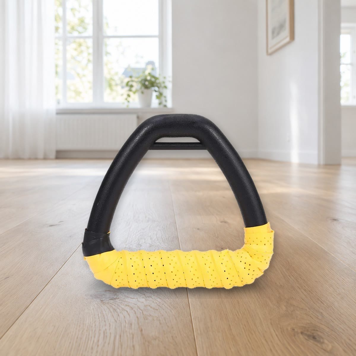 Ét trekantet håndtag med gul griptape viklet om grebet, stående på et gulv i lys eg