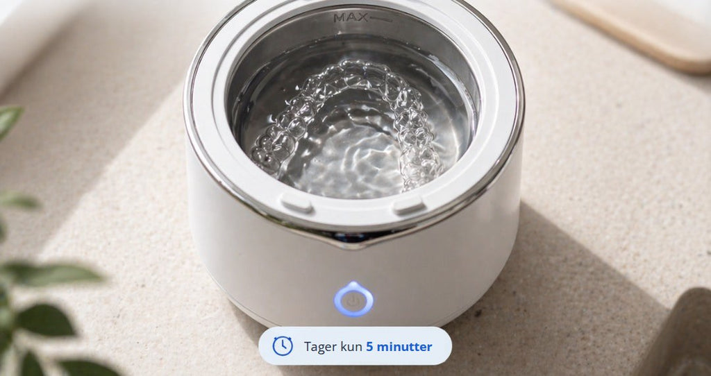 Ultralydsrenseren fyldt med vand på et bord, med teksten »Tager kun 5 minutter«