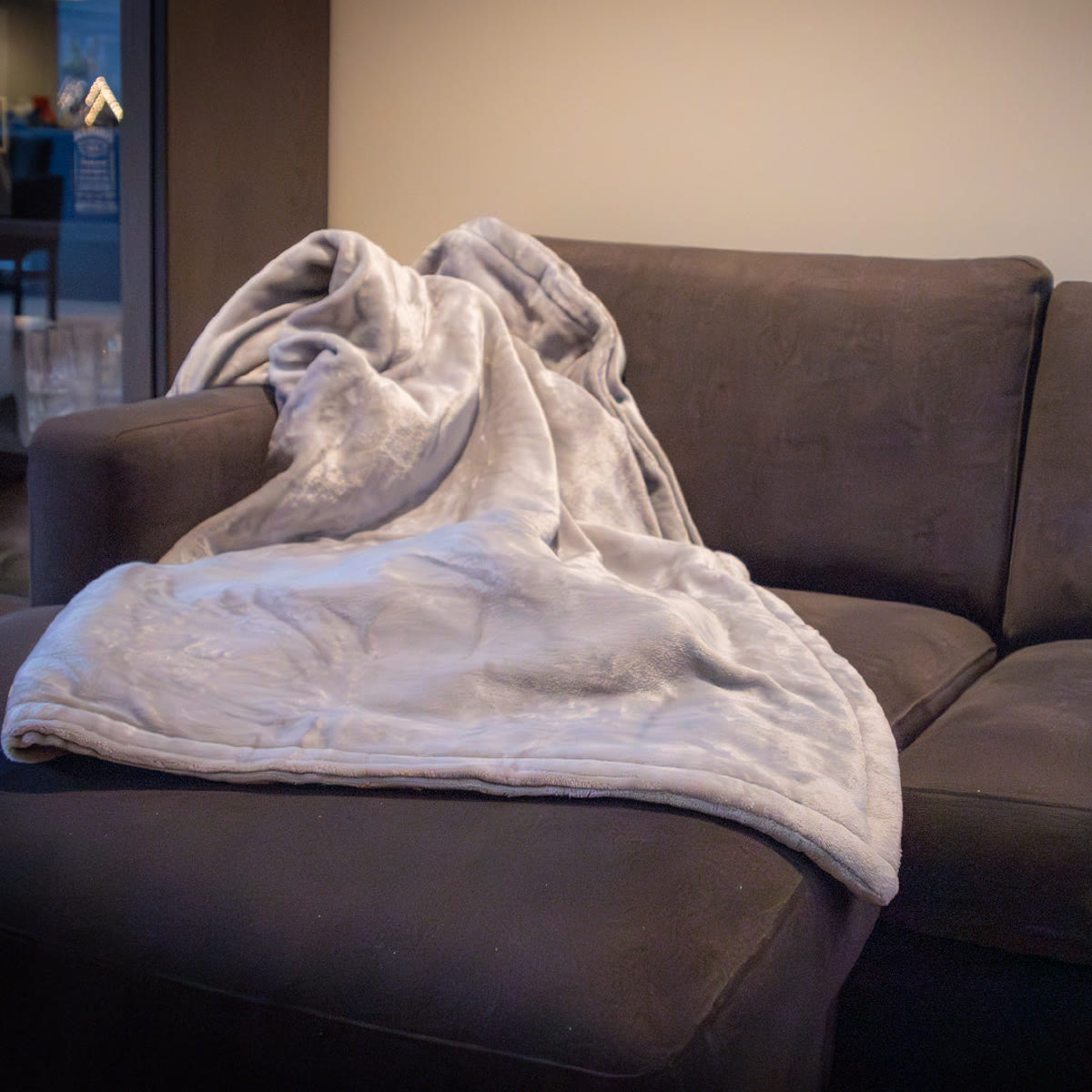 Varmetæppet lagt over ryggen og sædet på en mørk sofa
